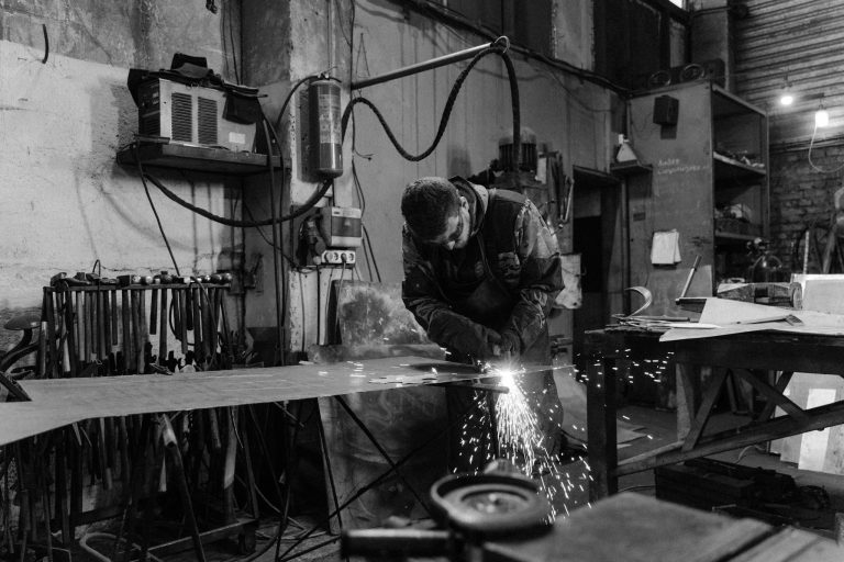 A welder working in a workshop, sparks flying as metal is cut with precision.