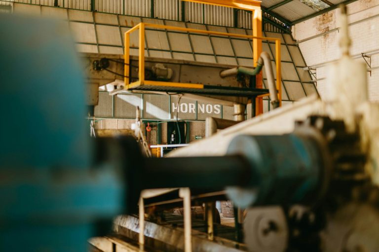 Close-up of heavy machinery inside an industrial factory with focus on ironworks and conveyor systems.